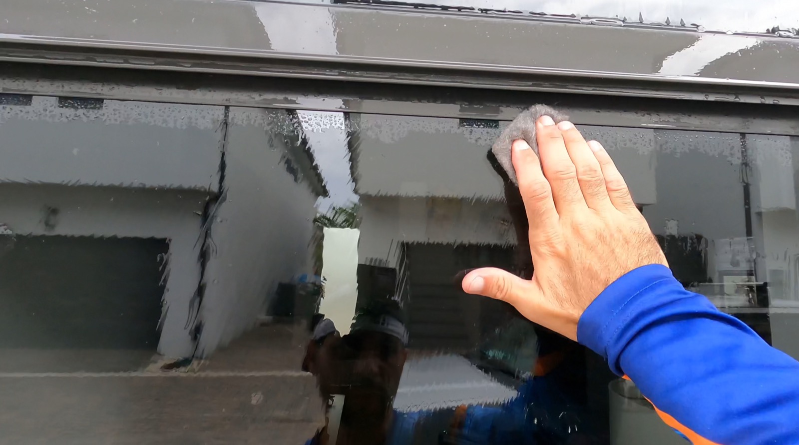 Shiny Windows technician polishing hard water mineral stains off a window with fine restoration pads in Miami